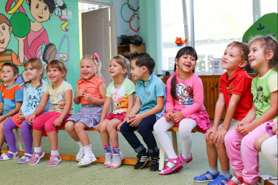 Lachende Kinder sitzen in einer Gruppe auf einer Bank